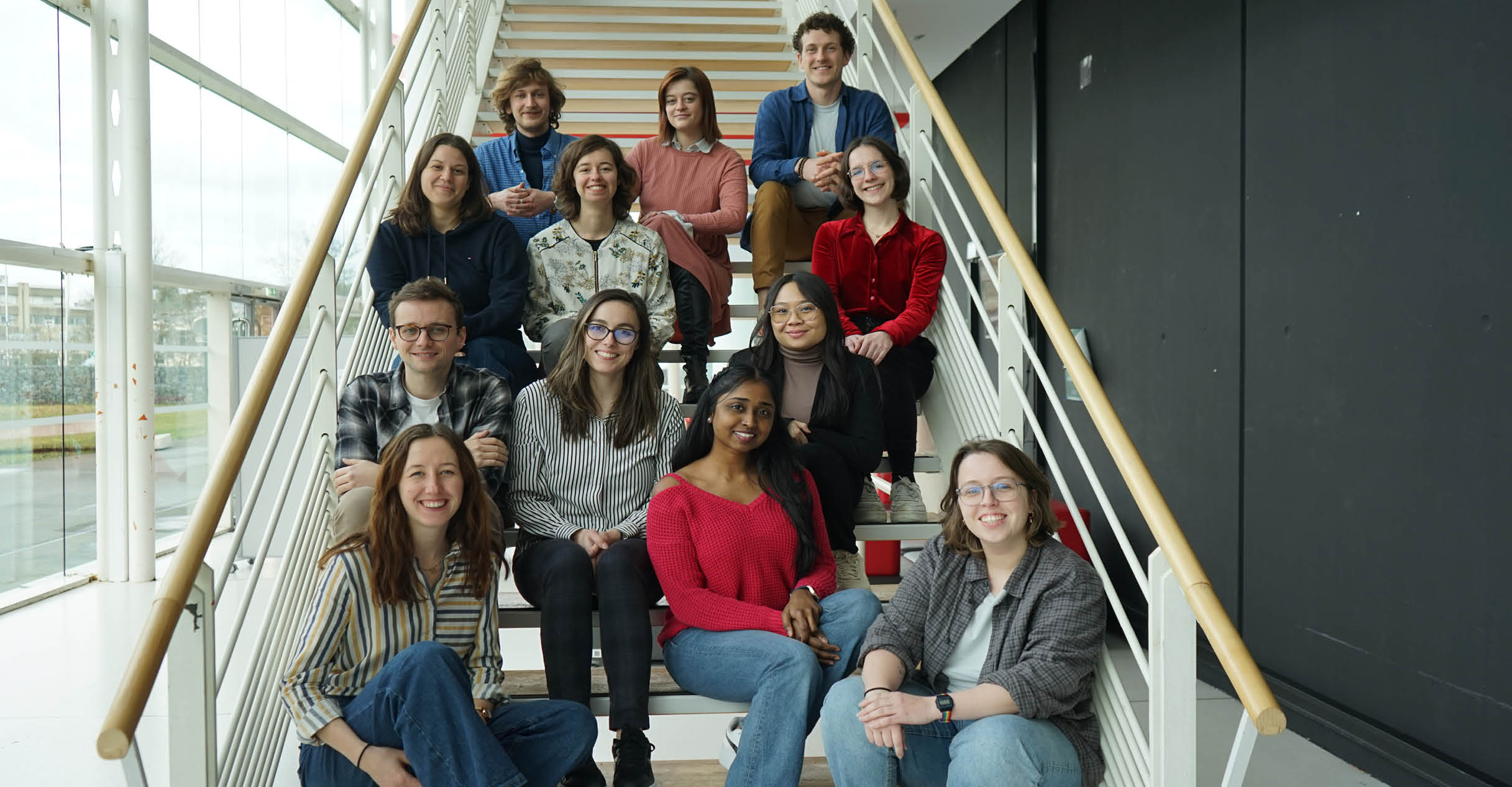 Photo des 12 finalistes du concours MT180 qui sont assis dans des escaliers.